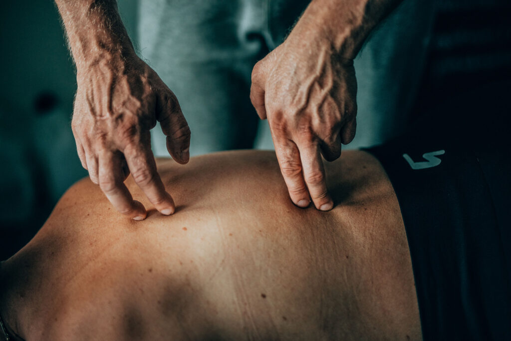 Osteopaatti koskettaa käsillään asiakkaan selkää