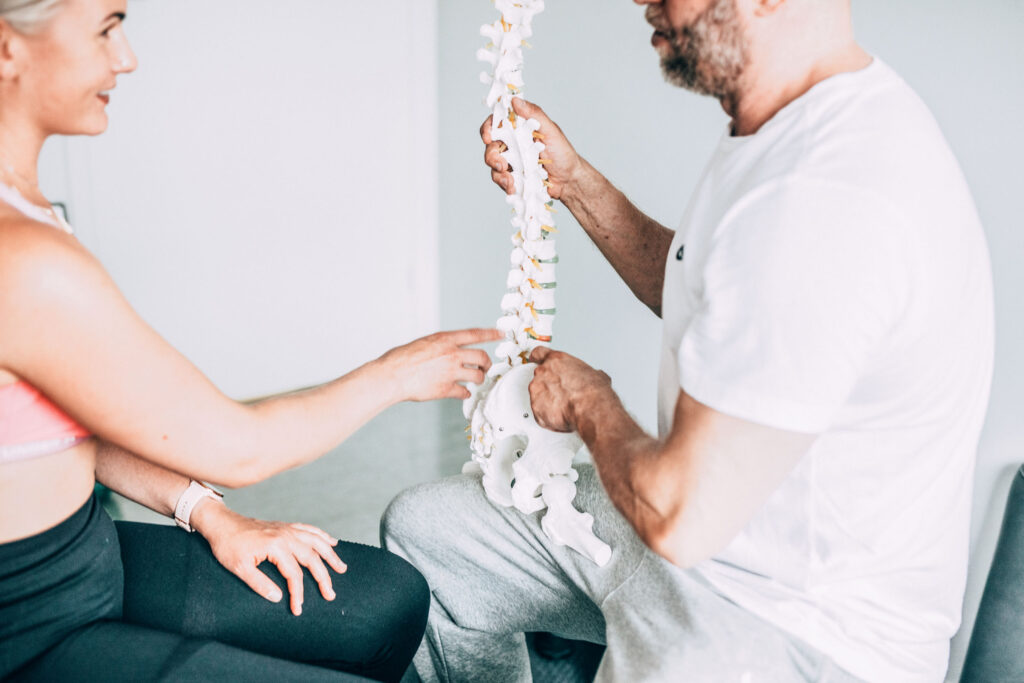 Naisen selkäkipu säteilee jalkaan. Osteopaatti koskettaa naisen selkää ääniraudalla ja tutkii kivun syytä.